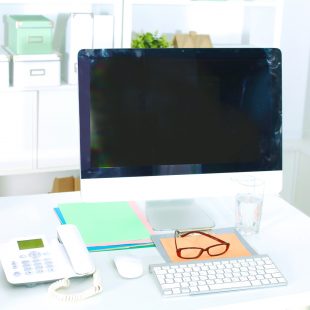 Office table with blank notepad and laptop
