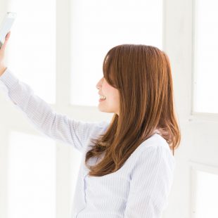 スマホで自撮りする女性